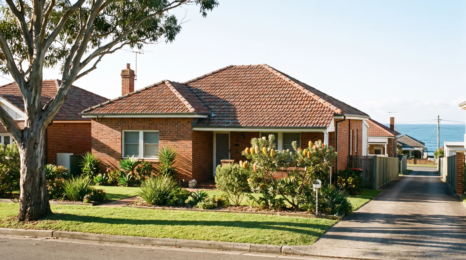 A classic Newcastle brick-and-tile home with a terracotta roof on a quiet suburban street